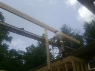 Carpenter setting a ridge beam over a new addition frame — Ice Dam Removal by Roofing Brothers in Mantee