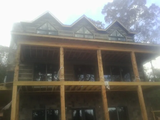 Dormers and porch framing on a large log home under construction — Roof Coating work by our crew in Mantee