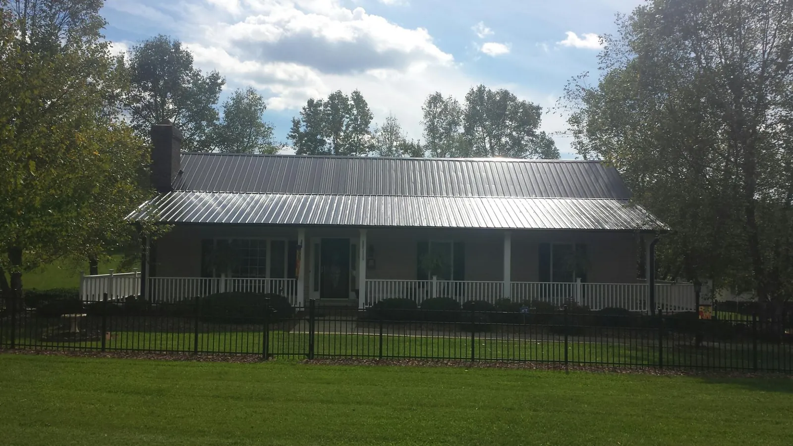 Gray metal roof on a brick ranch with a full width front porch — Gutter Guard Installation work by our crew in Mantee