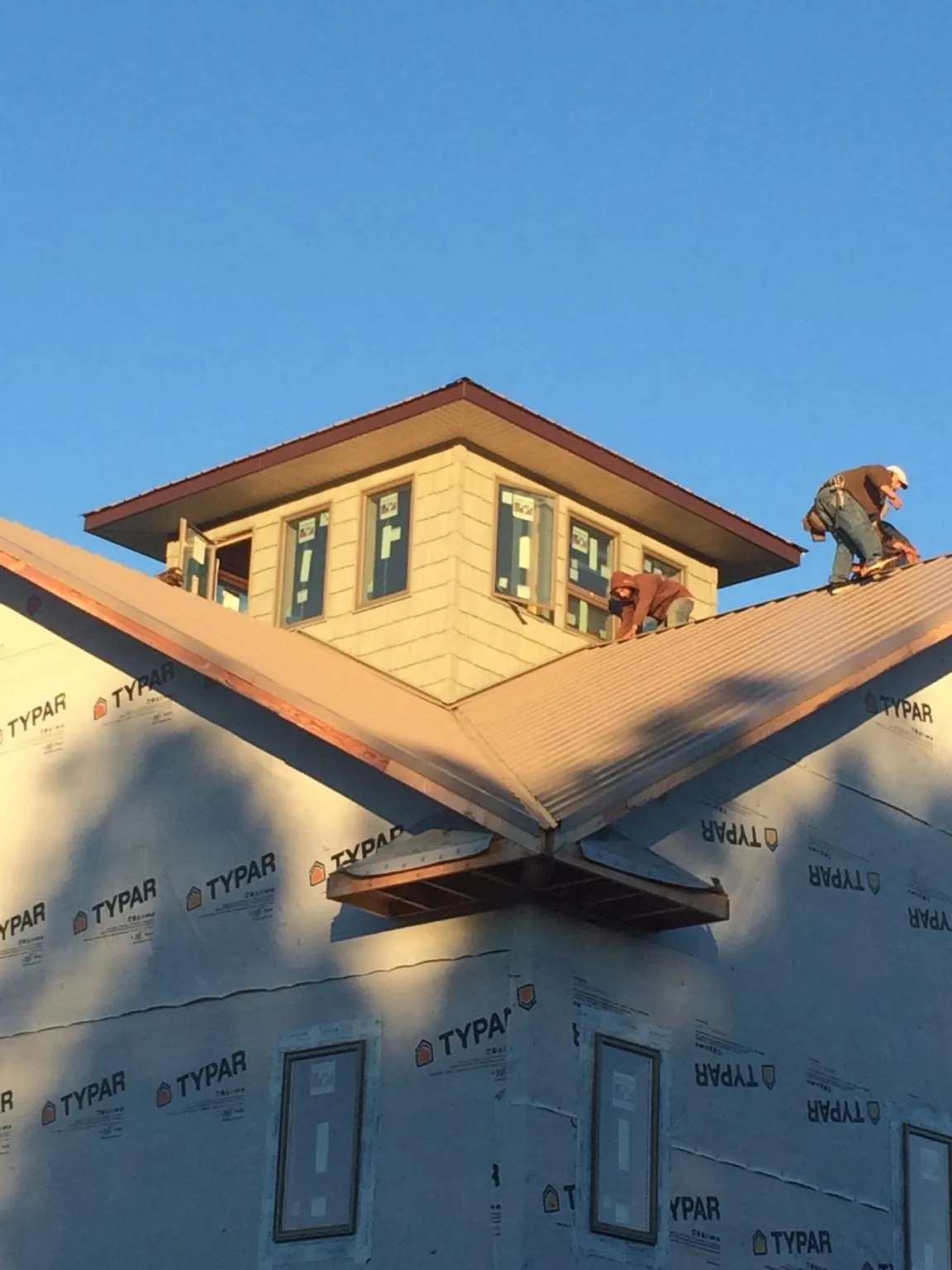 Roofers working around a rooftop cupola on a new metal roof at sunset — Roof Waterproofing in Mantee by Roofing Brothers